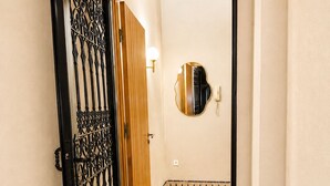 A hallway with a black metal gate, a wooden door, a mirror on the wall, and a tiled floor. - Cosy villa targa garden 5G IPTV (Marrakech)