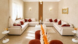 A modern living room with a sofa set, a coffee table, and a dining area set for a meal. - Cosy villa targa garden 5G IPTV (Marrakech)
