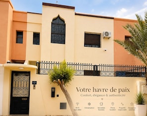 A hotel facade with a black gate, a sign indicating 'Villa Neumann 731', and a signboard with amenities like Wi-Fi, heating, and room service. - Cozy Villa Targa Garden 5G IPTV (Marrakech)