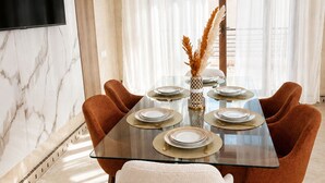 A dining area with a glass table, six chairs, and a TV mounted on the wall. - Cosy villa targa garden 5G IPTV (Marrakech)