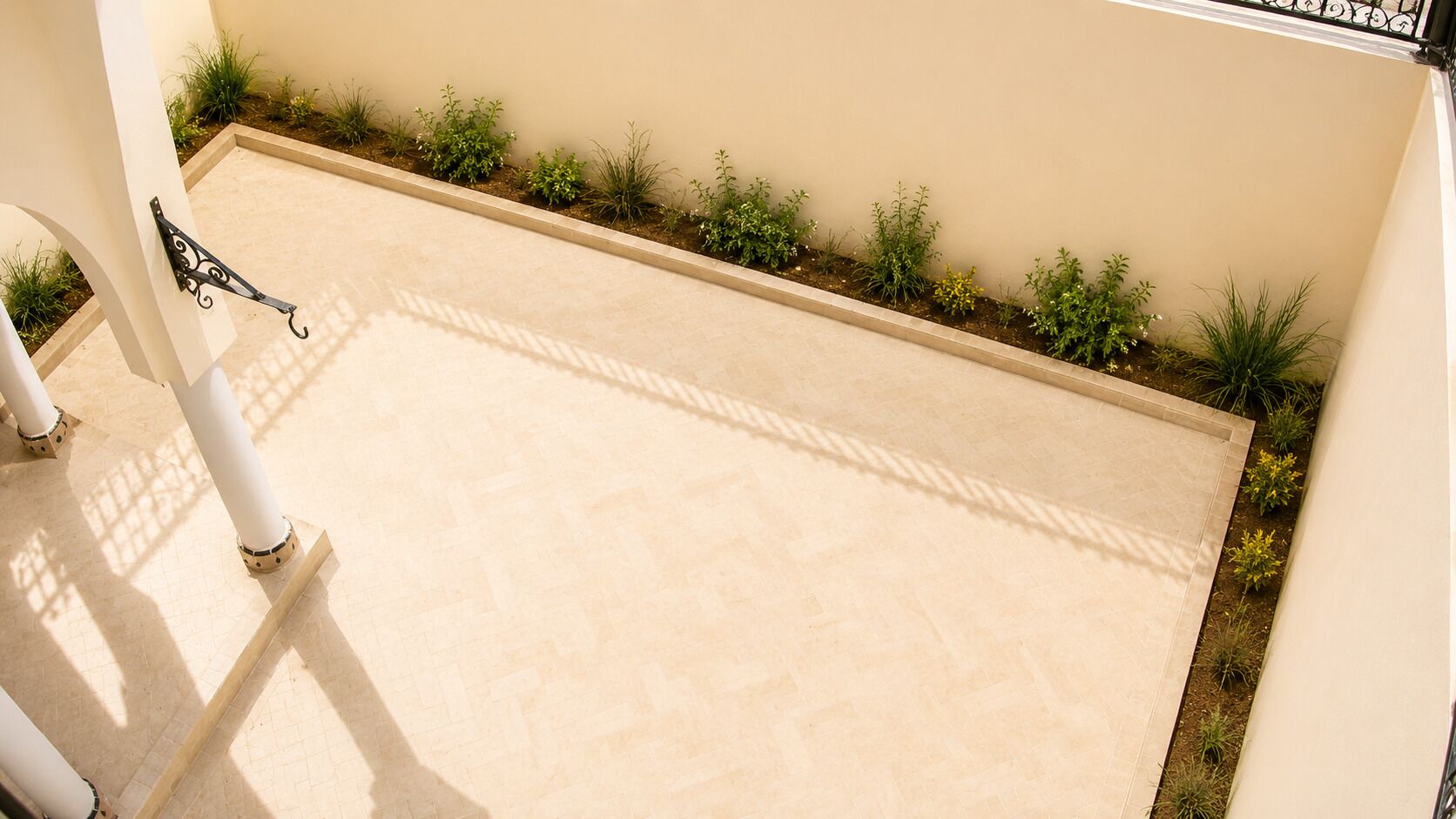 A flat roof terrace with a tiled floor, a metal railing, and a row of small plants along the edge.