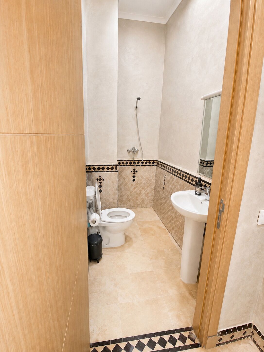 A bathroom with a toilet, sink, shower, and a tiled floor.