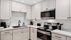 Une cuisine moderne avec des meubles blancs, une cuisinière en acier inoxydable, un four à micro-ondes et un évier.