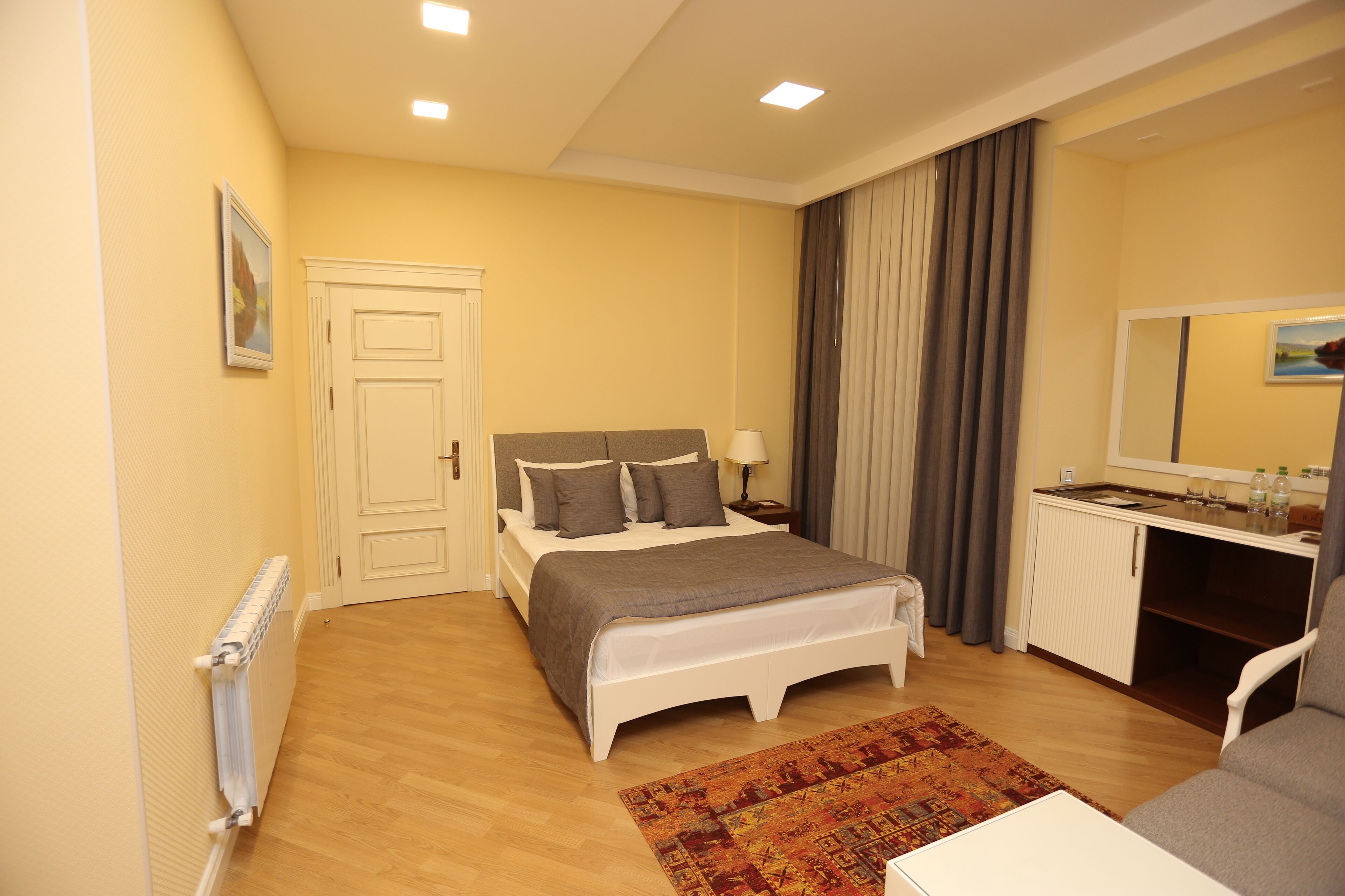 Une chambre à coucher comprenant un lit, une table de chevet, une lampe et un petit bureau avec un miroir.