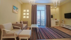 A living room with a sofa, armchairs, a coffee table, a TV, and a patterned rug. - ILK INN HOTEL (Qusar)