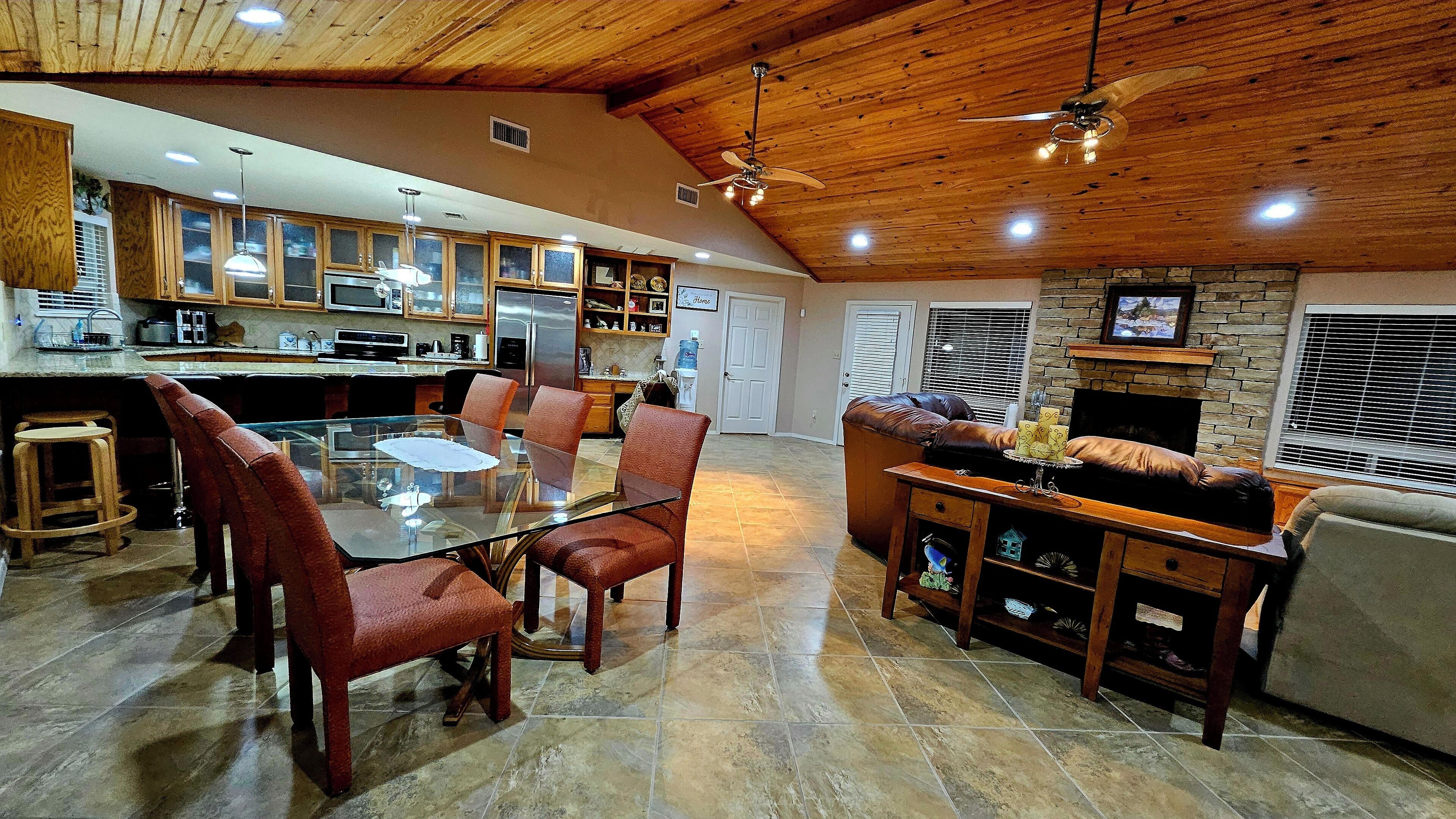 A spacious kitchen with a dining area, a fireplace, and a stone accent wall.