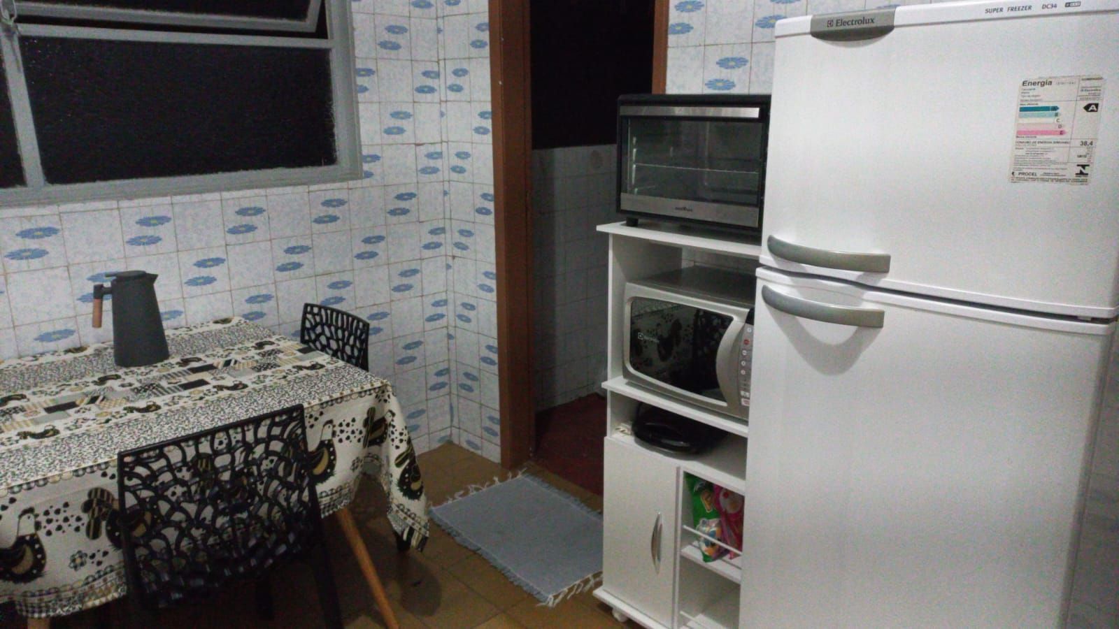 Cozinha compacta com geladeira, micro-ondas e forno pequeno.