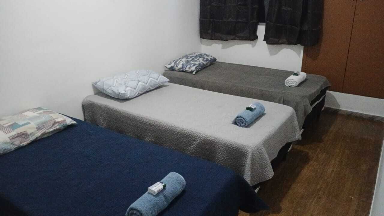 Una habitación con dos camas individuales, cada una con una almohada y una toalla enrollada.