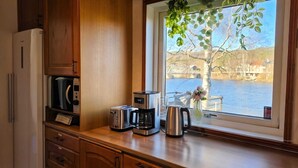 A kitchen with a view of a lake, a toaster, a coffee maker, and a refrigerator. - Riverside Villa with a Private Jetty and Scenic Views (Torpshammar)