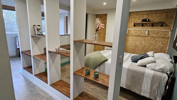 Ein modernes Schlafzimmer mit Bett, Regalen und einer Holzvertäfelung.