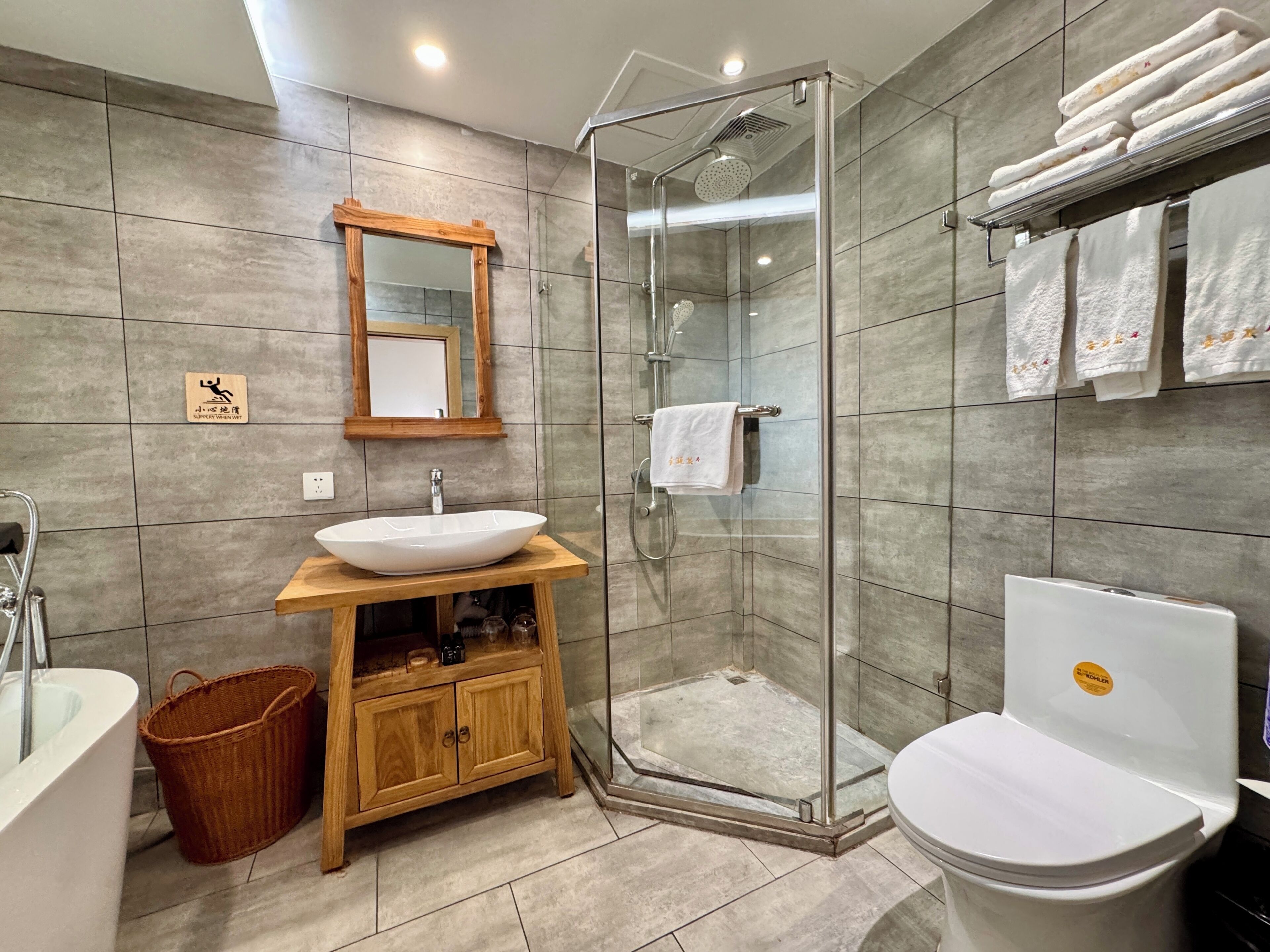 A modern bathroom with a glass-enclosed shower, a wooden vanity, a white sink, and a toilet.