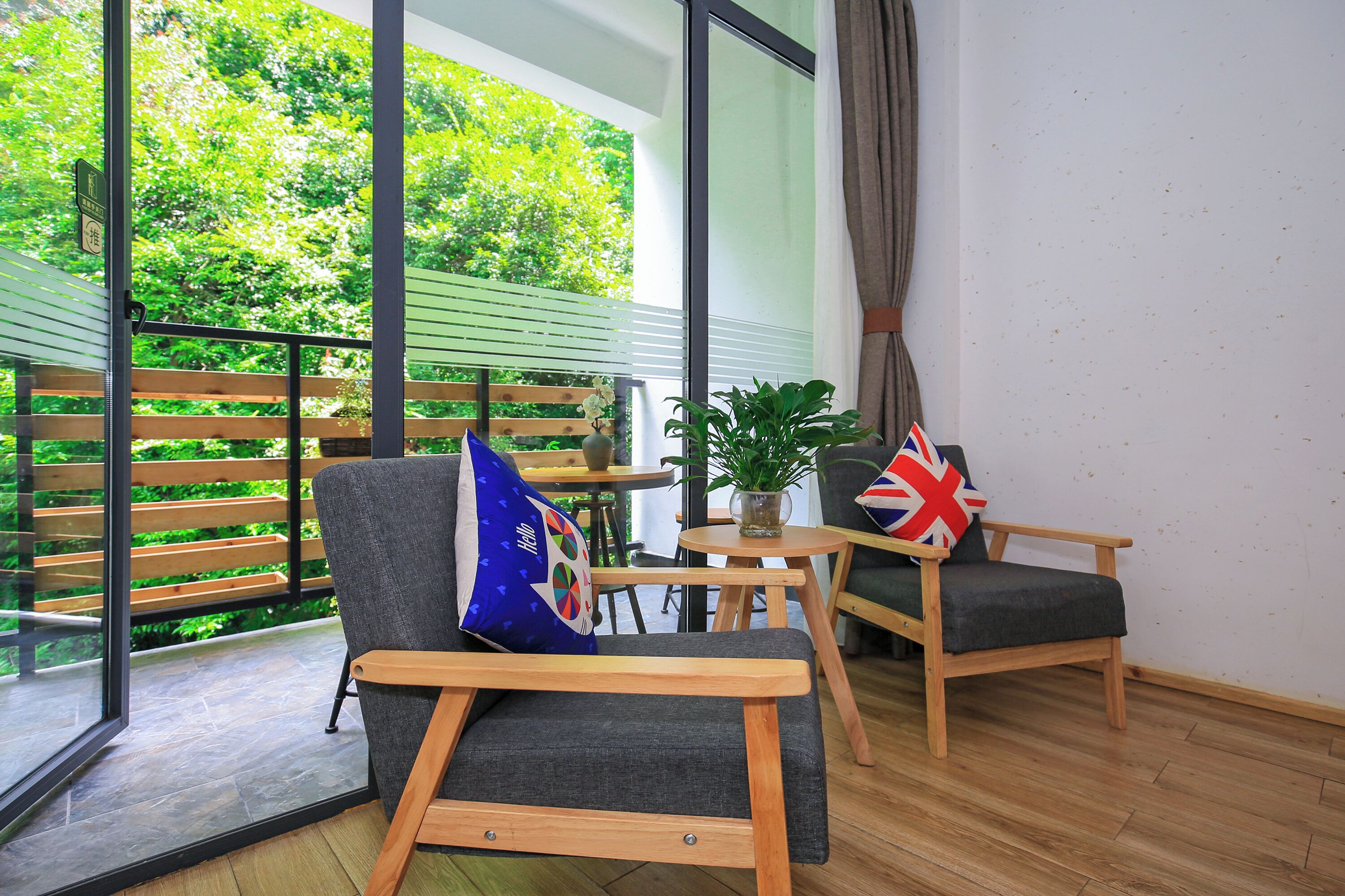 A balcony with a wooden railing, a chair with a cushion, a small table with a potted plant, and a cushion with a flag design.