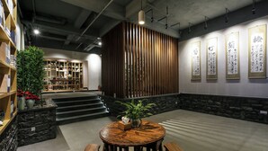 A modern interior with a round wooden table, bookshelves, a potted plant, and a staircase leading to another level. - Tea House Inn West Street Yangshuo (Guilin)