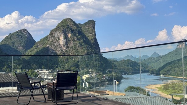 Un balcon avec des chaises et une vue sur une rivière et des montagnes.