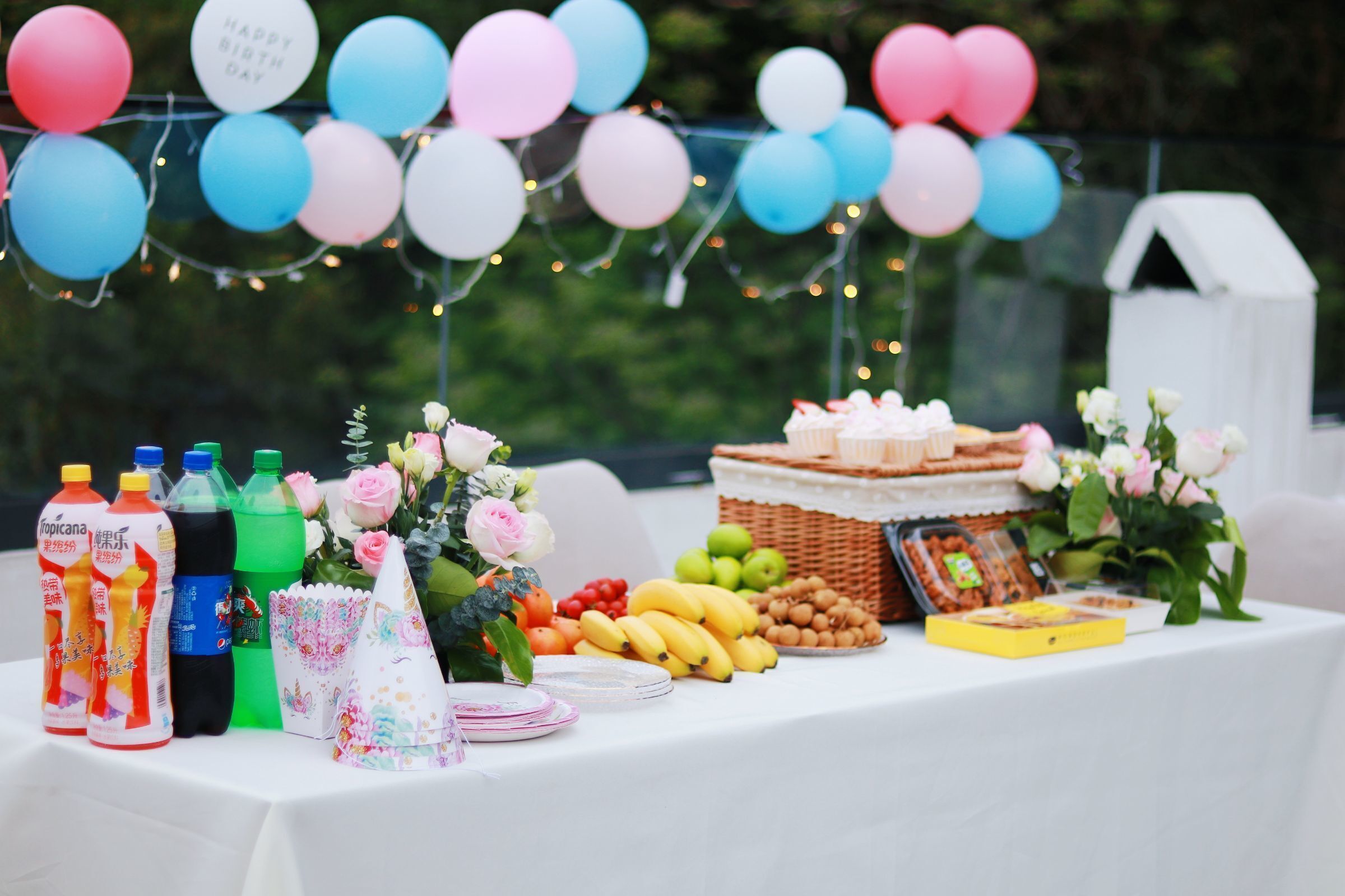 Une table garnie de nourriture et de boissons, décorée de ballons et de fleurs.