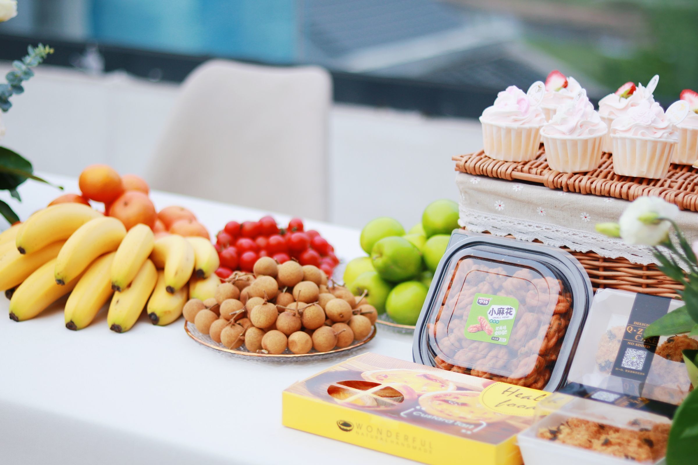 Ein Tisch mit verschiedenen Speisen, darunter Bananen, Äpfel und verpackte Snacks.