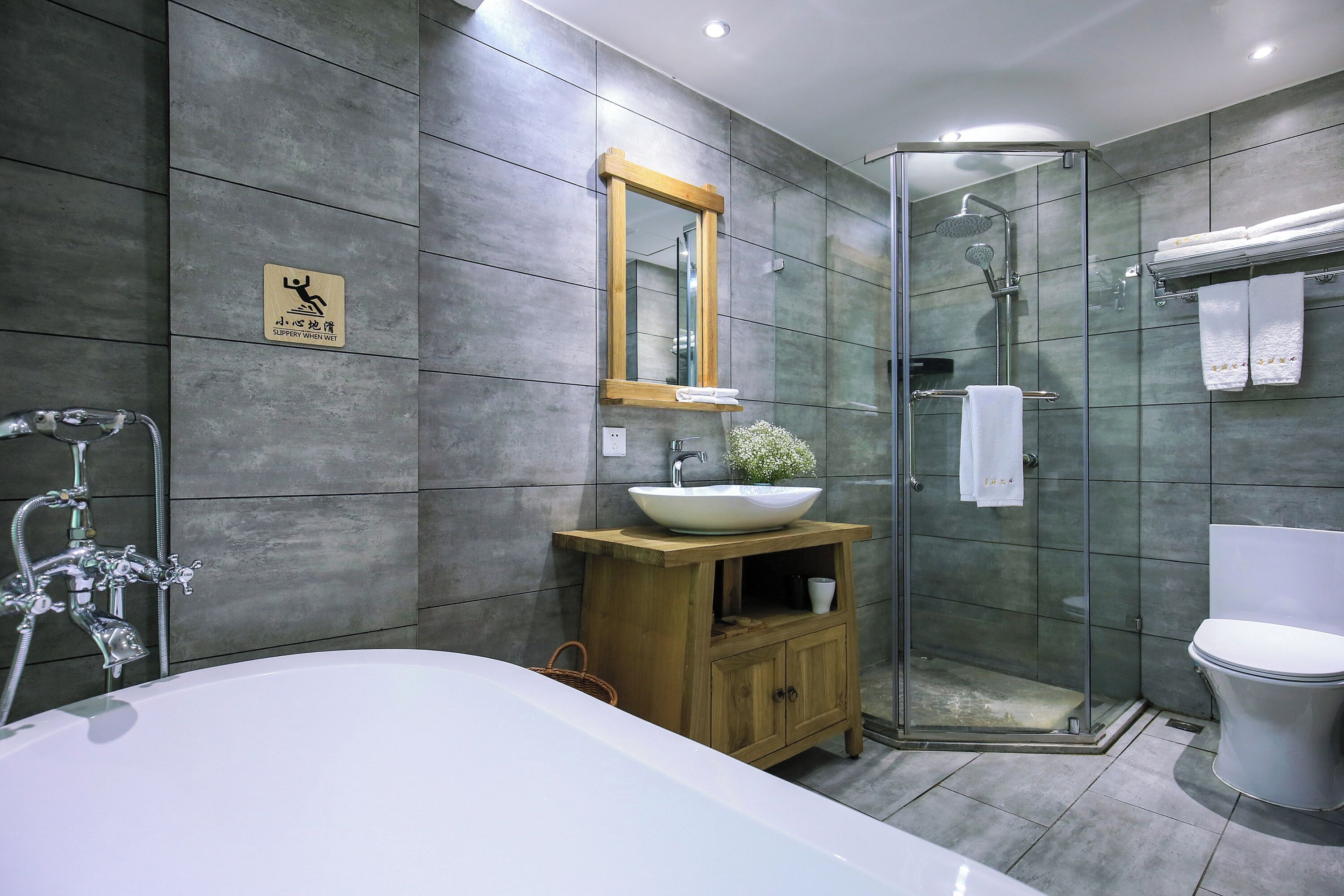 A modern bathroom with a bathtub, a glass-enclosed shower, a wooden vanity with a sink, and a toilet.