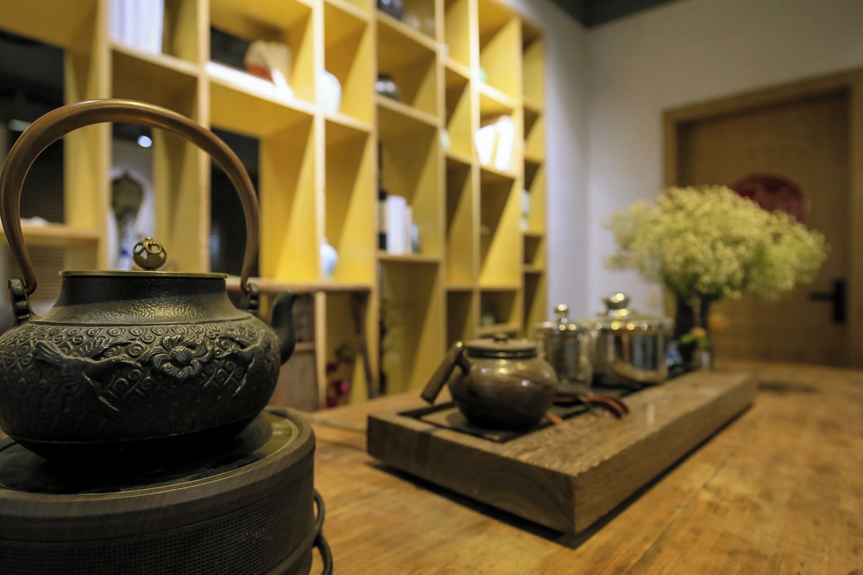 Un juego de té tradicional sobre una mesa de madera, con una estantería al fondo.