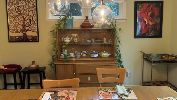 A dining area with a wooden table, chairs, and a glass display cabinet with tea sets. - Spacious 5-bedroom house in serene Montclair, close to NYC and World Cup arena (Montclair)