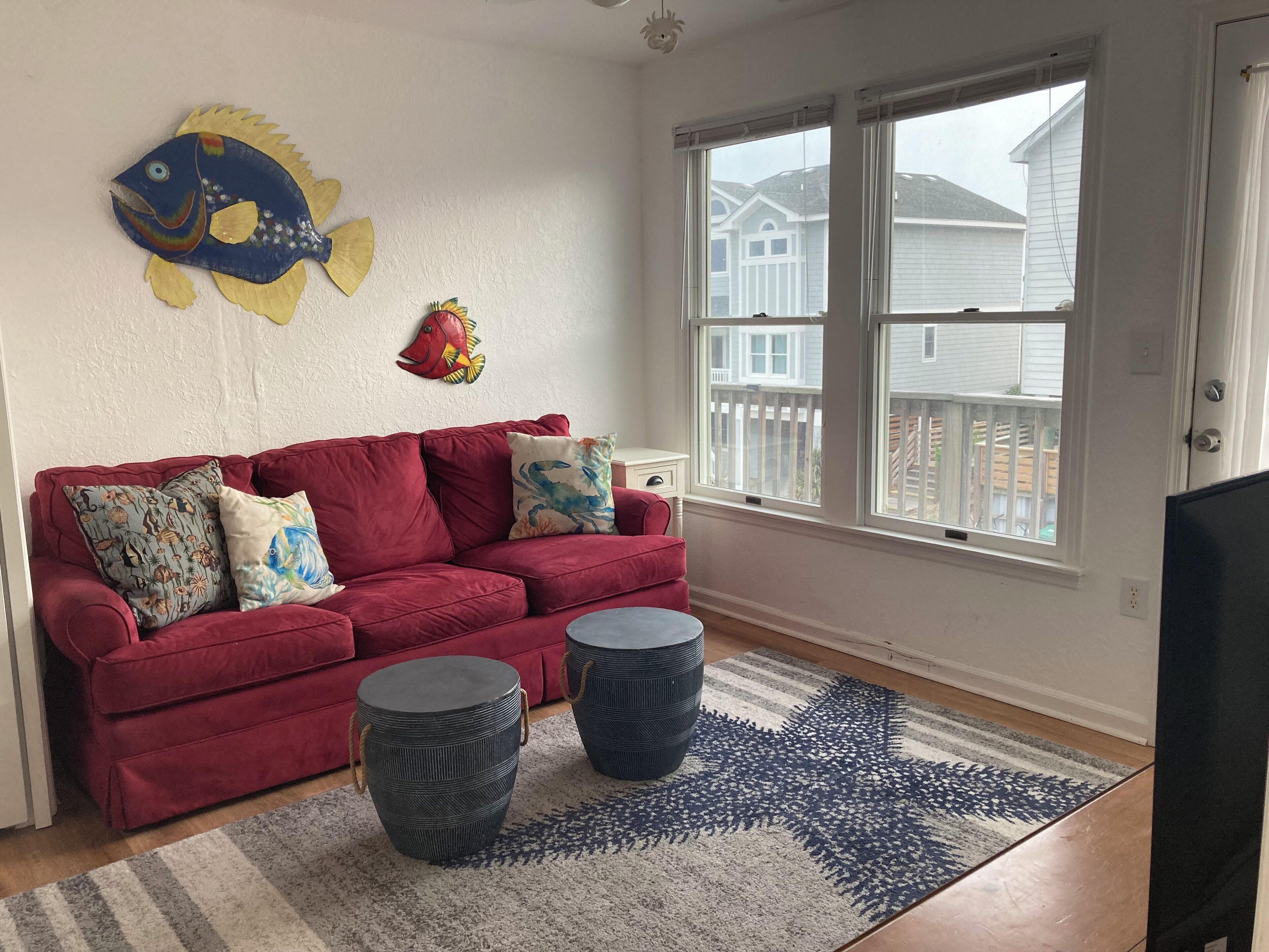 A living room with a red sofa, two round side tables, a patterned rug, and a fish wall decoration.