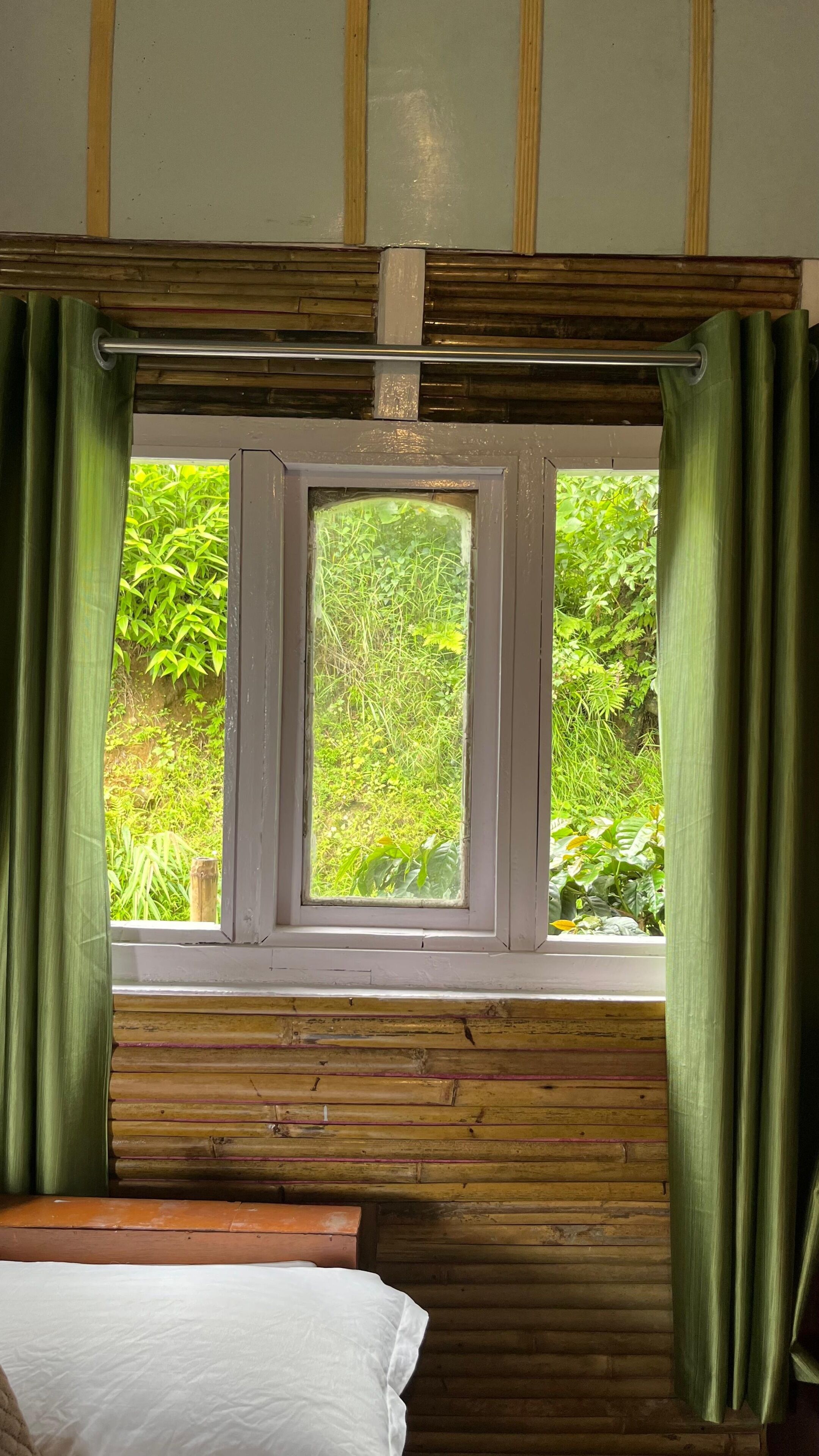 Una habitación con ventana, paredes de madera y una cama.