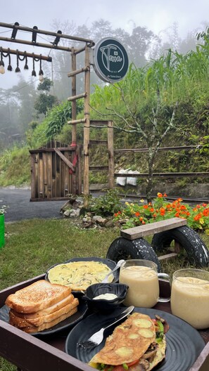 A breakfast setup with toast, omelette, and beverages on a table outdoors. - Terra Mist by Terra Stays (Kalimpong)