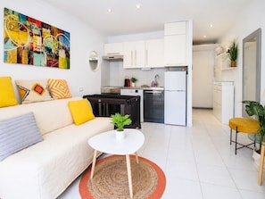 Eine moderne Wohnung mit Wohnbereich, Küchenzeile und Essplatz.