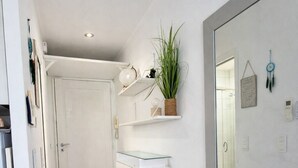 Ett modernt kök med vita skåp, en köksö med glasskiva och en stor spegel som reflekterar rummet.