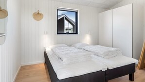 Een slaapkamer met een bed, een raam met uitzicht op een gebouw en een kledingkast.