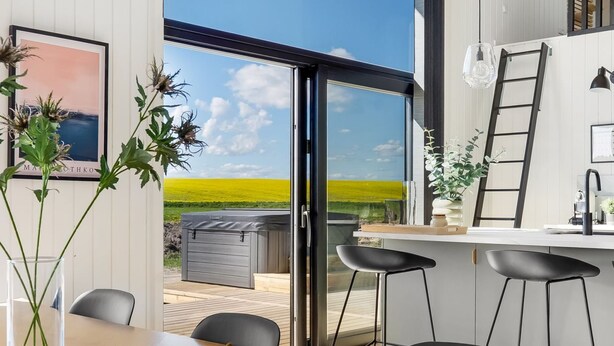 Een moderne keuken met een groot raam, een jacuzzi en een eethoek met een schaal fruit.