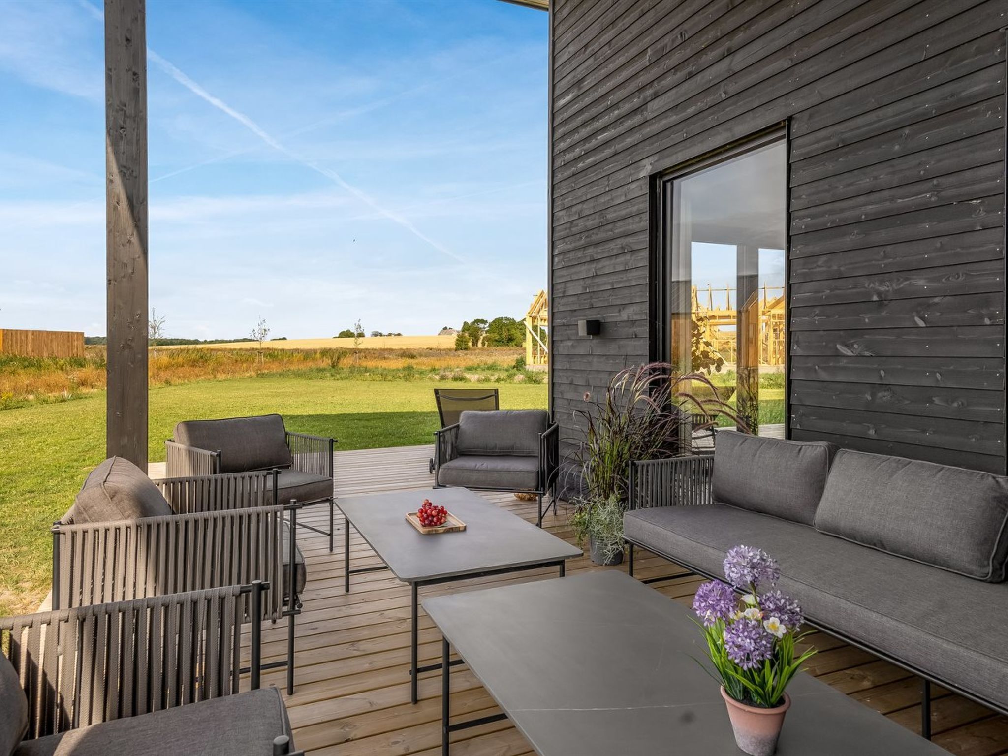 A modern outdoor seating area with a wooden deck, a sofa, and chairs.