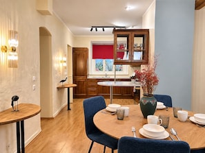 A modern dining area with a round table set for four, surrounded by blue chairs. - 1-bedroom in Old Town (Tallinn)