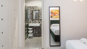 Ein modernes Badezimmer mit Glasdusche, einem weißen Waschbecken und einem großen Spiegel.