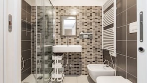 Ein modernes Badezimmer mit Duschkabine aus Glas, einem weißen Waschbecken, einer Toilette und einem Spiegel mit Zierrahmen.