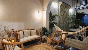 A cozy seating area with a hammock, a sofa, and a chair, surrounded by potted plants and a patterned rug. - Private house with swimming pool, jacuzzi and terrace in walled Cartagena (Cartagena de Indias)
