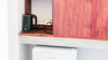 A wooden cabinet with two bottles, a kettle, and a small refrigerator with a 'Powerful Cooling' label.