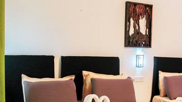 A hotel room with a bed, pillows, a blanket, a wall-mounted artwork, and a power outlet.
