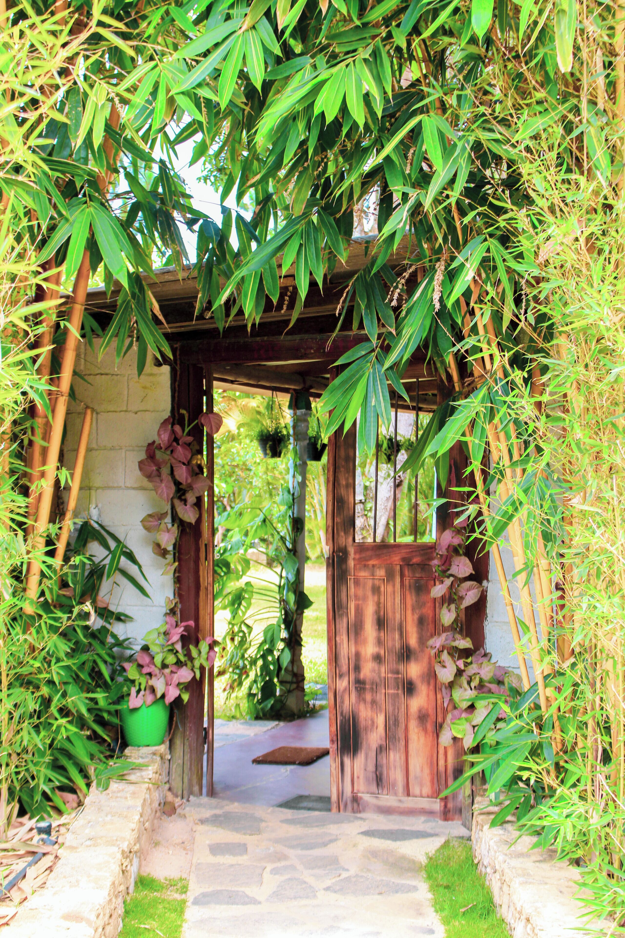A wooden archway leading to a stone pathway.
