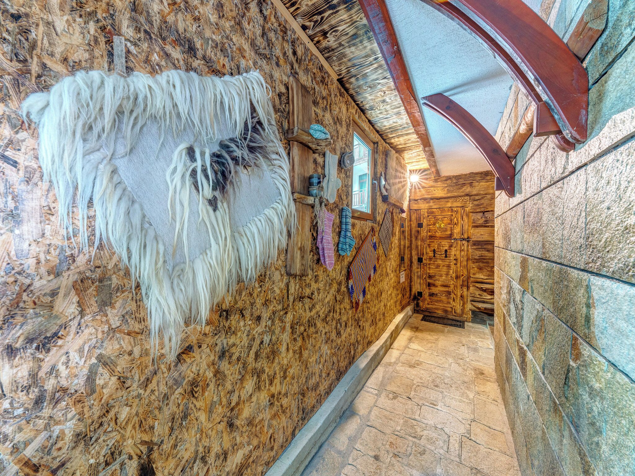 A hallway with wooden walls, a stone floor, and a rustic door.