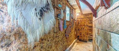 A hallway with wooden walls, a stone floor, and a rustic door.