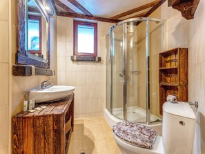 A bathroom with a glass shower enclosure, a wooden vanity, and a toilet with a patterned seat. - Alpine Villas Pamporovo (Smolyan)