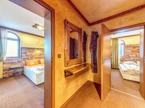 A bedroom with a wooden headboard, a wooden bench, and a large mirror. - Alpine Villas Pamporovo (Smolyan)