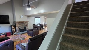 Una sala de estar moderna con una escalera, una chimenea y un comedor.