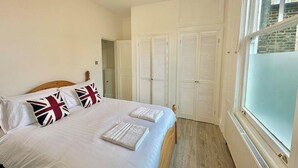 A bedroom with a bed, pillows, a window, and a door. - Bright Apartment Stockwell Station Nearby (London)