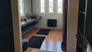 A modern bathroom with a black countertop, a copper vessel sink, a large mirror, and three windows. - Magnificent contemporary Basque house with pisicine in a green setting (Ustaritz)