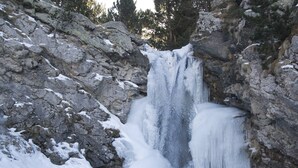 A waterfall cascading over a rocky cliff into a frozen pool surrounded by snow-covered terrain and trees. - Renovated studio cabin near slopes, 4 pers. (Bolquère-Pyrénées 2000)