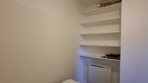 A small, narrow room with white walls and a white radiator. There are white shelves along one wall, with some items on the top shelf. - Renovated studio cabin near slopes, 4 pers. (Bolquère-Pyrénées 2000)