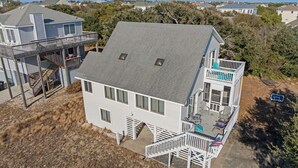 A two-story house with a balcony, a deck, and a small pool area. - Serenity Now: Oceanside | Screened in Porch | (Duck)