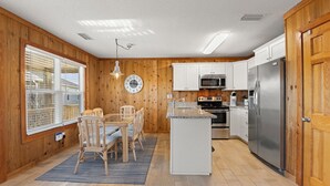 Una cucina con pareti in legno, un'area pranzo con tavolo e sedie, un frigorifero e un forno a microonde.