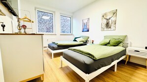 Ett modernt sovrum med två enkelsängar, ett skrivbord och ett element.